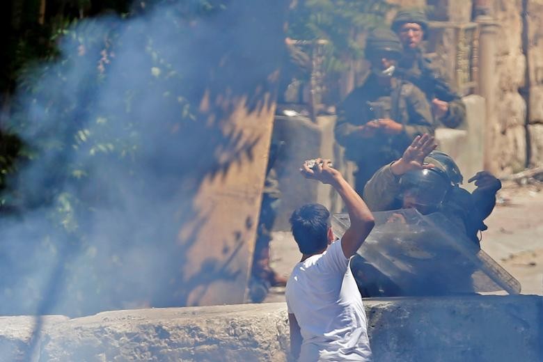 A Palestinian demonstrator hurls stones at Israeli soldiers during a protest in Hebron in the Israeli-occupied West Bank. REUTERS/Mussa Qawasma  